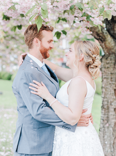 bridea and groom smile at each other under falling cherry blossoms in victoria