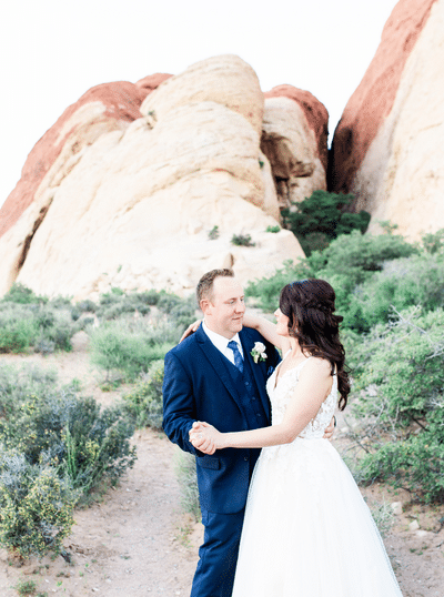 Couple dancing in front of a pink rocky outcrop at their elopement