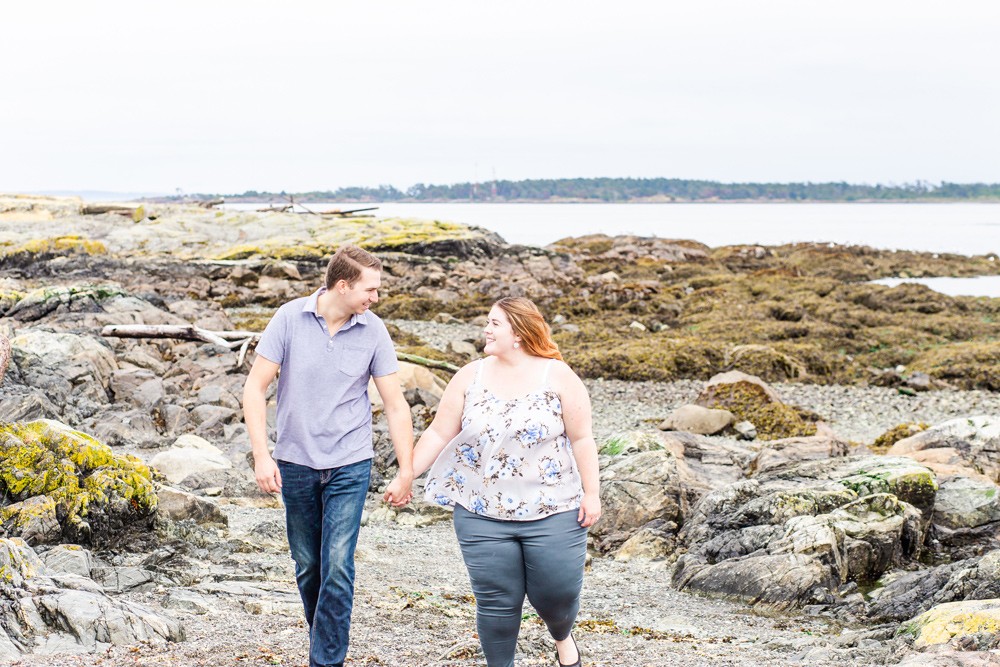 Cute couple walking hand in hand on a rocky beach in victoria